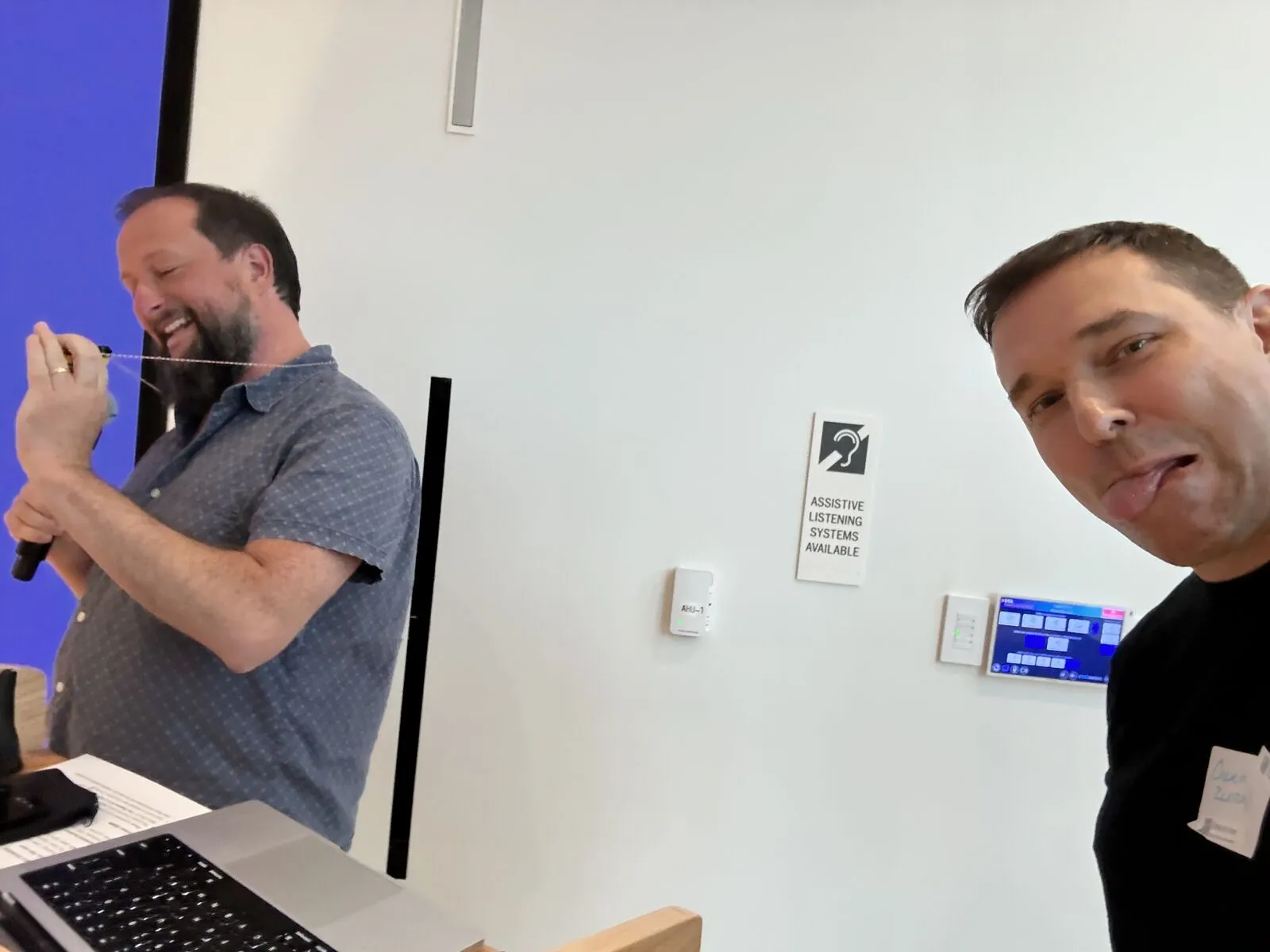 An organizer pulling a face in a selfie with a pitcher at the microphone