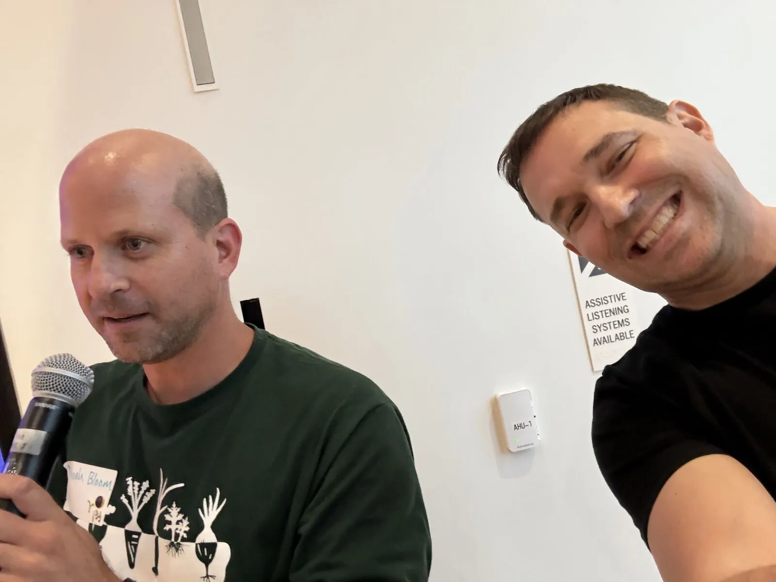 An organizer's selfie with a pitcher in a green T-shirt holding the microphone