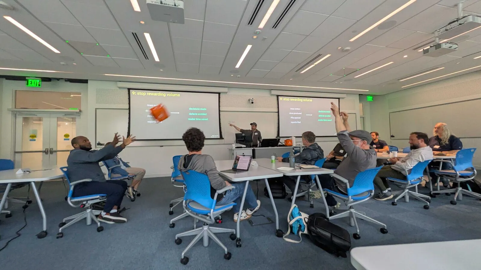 Attendees raising their hands during a session in a lecture room