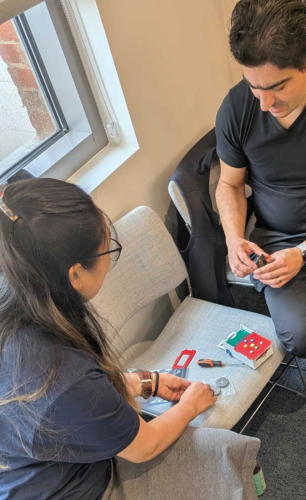 Two attendees assembling small electronics kits on a sofa