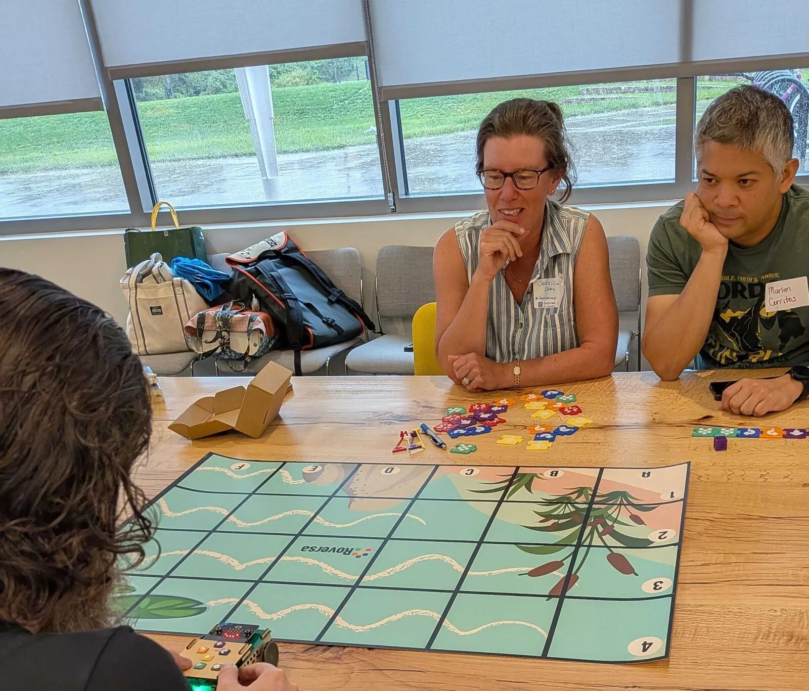 Attendees around a robot game mat, coding pieces scattered across the table