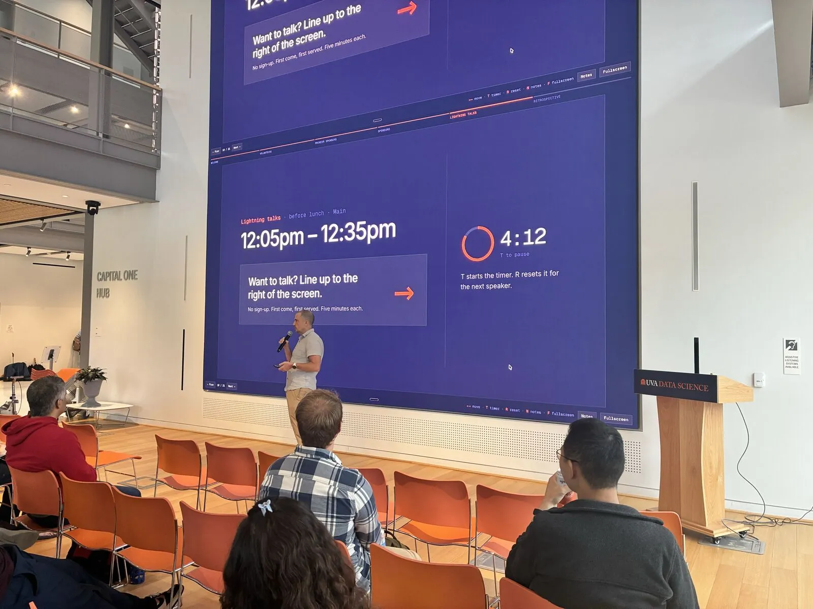 A lightning talk in the main hall, the video wall showing the lightning-talk timer