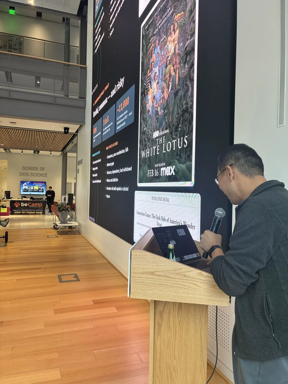 A speaker at the lectern in the main hall during lightning talks