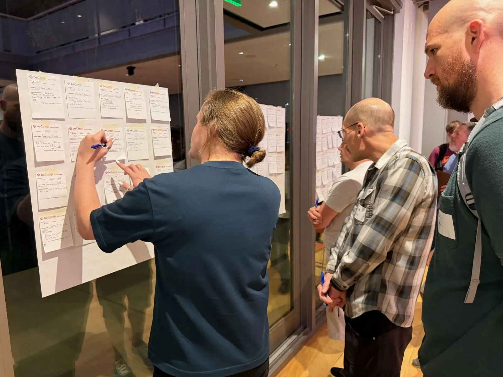 Attendees writing on and reading the pitch board during voting