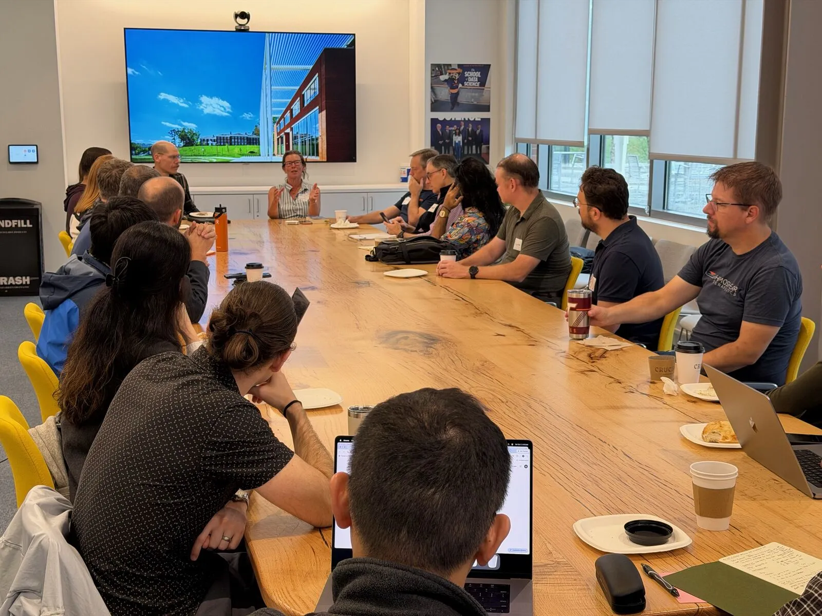 Attendees around a long wooden table in a conference room during a discussion