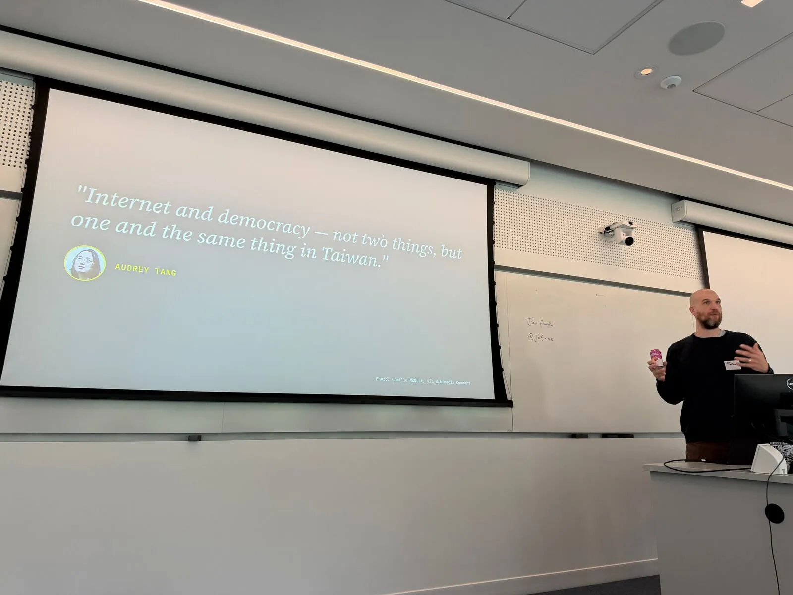 A presenter beside a slide quoting "Internet and democracy — not two things, but one and the same thing in Taiwan"