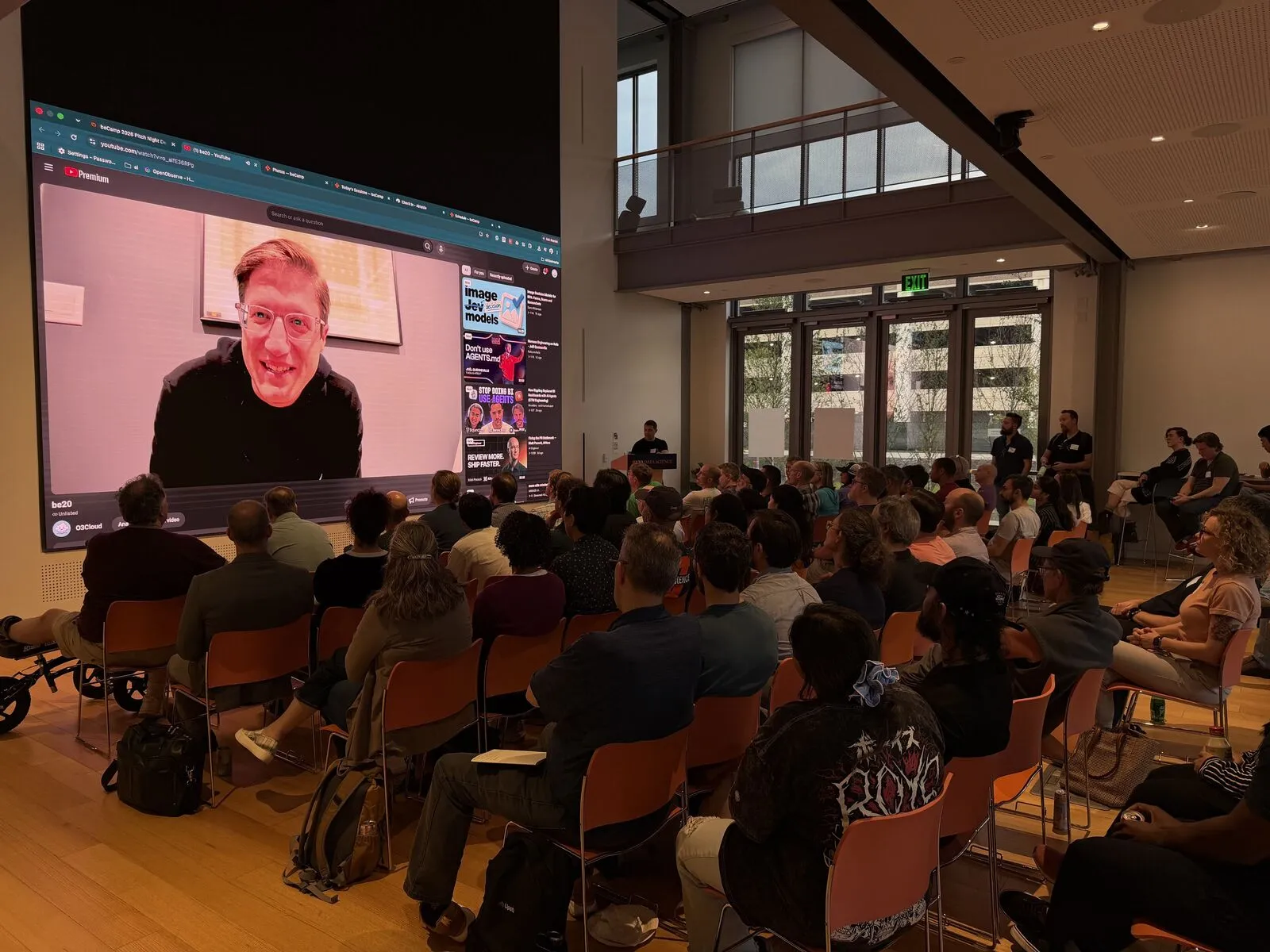 A remote speaker on the giant video wall, presenting to a packed hall